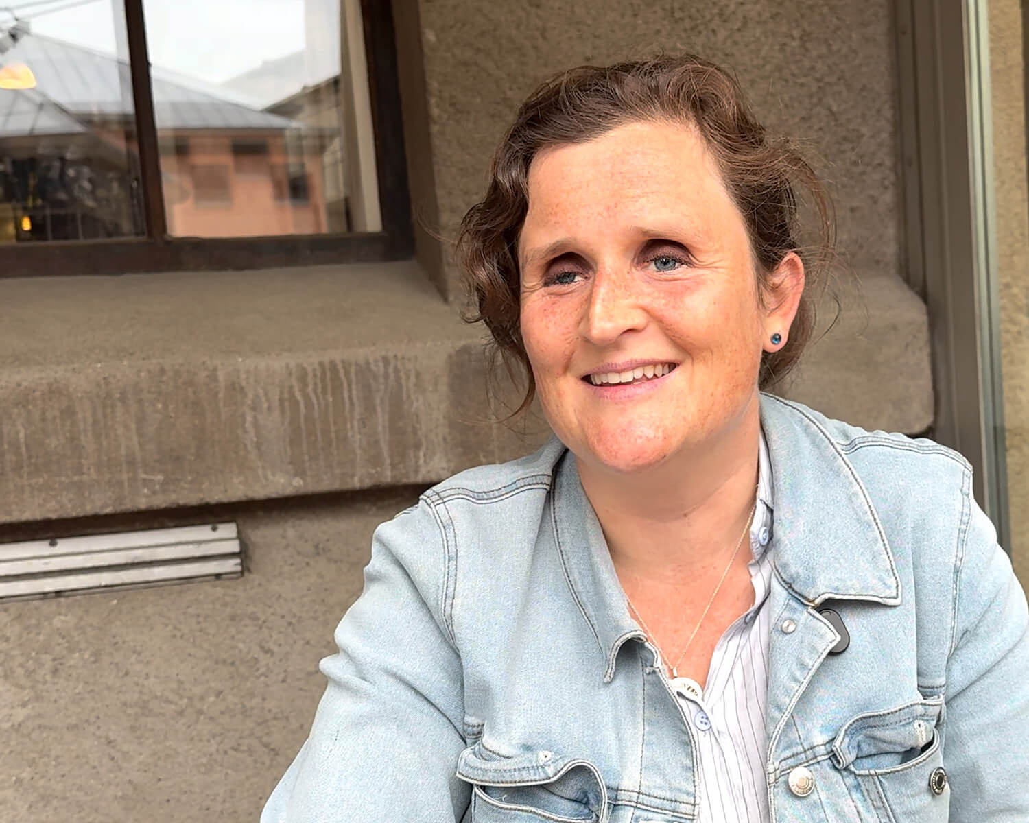 Ann-Sofie står med sin stok og rører ved to lyse heste